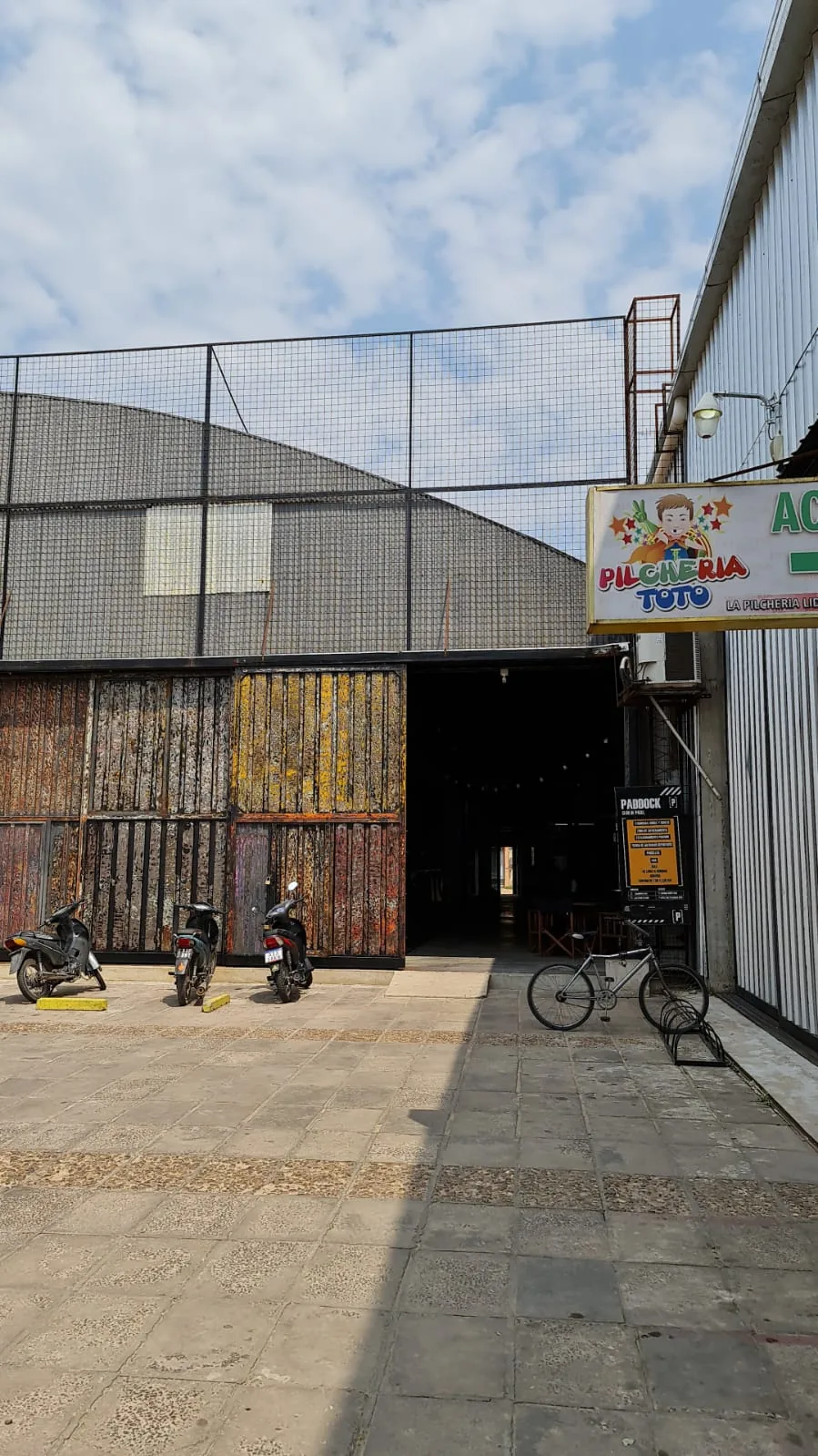 La entrada de Paddock sobre Av. Maipú, de día, con el cartel amarillo al lado del portón